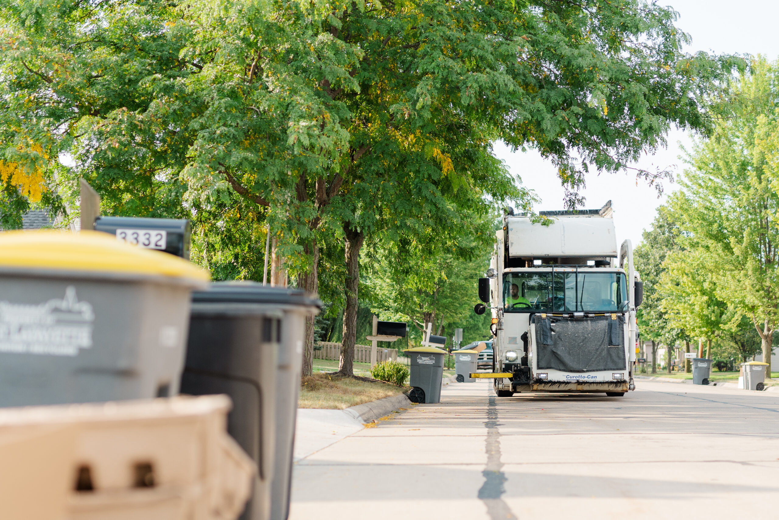 Truck collecting waste bins in suburban neighborhood